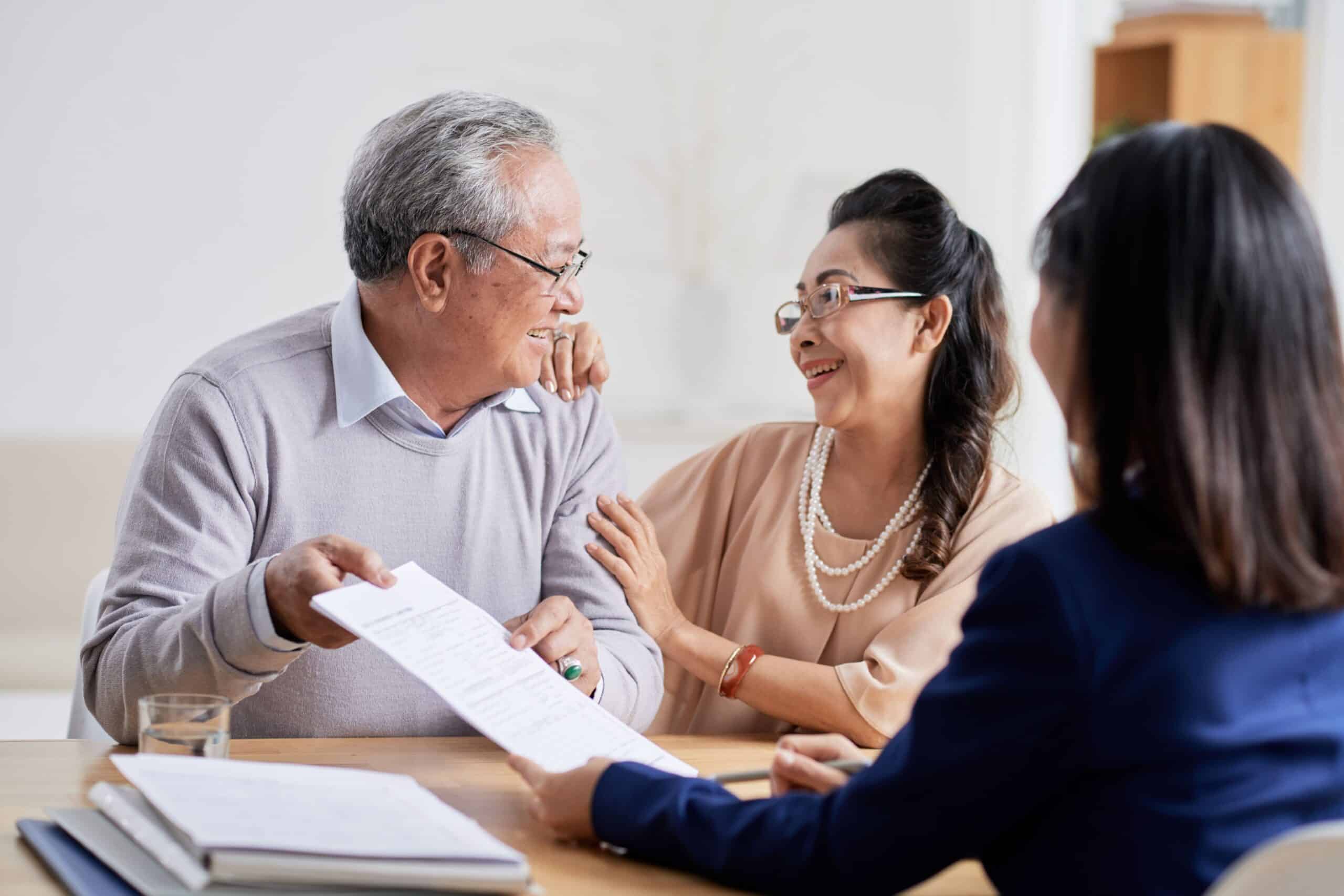 An Asian couple engages in a discussion with a financial advisor in a professional setting